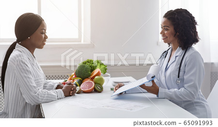 Two black ladies patient and doctor having conversation at clinic 65091993