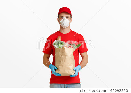Courier in rubber gloves and mask holds package 65092290