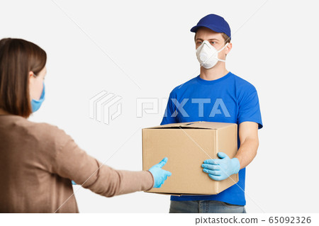 Client in protective mask, takes box from courier Client in protective mask, takes box from courier 65092326