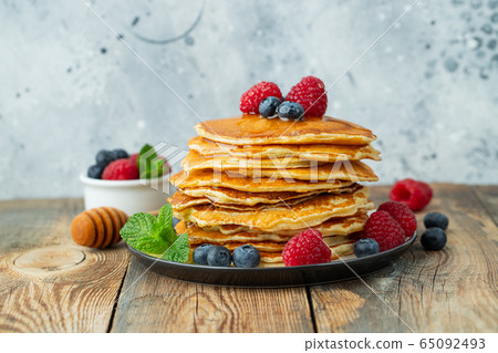 Delicious pancakes, with fresh berries and honey. Delicious pancakes, with fresh berries and honey. 65092493