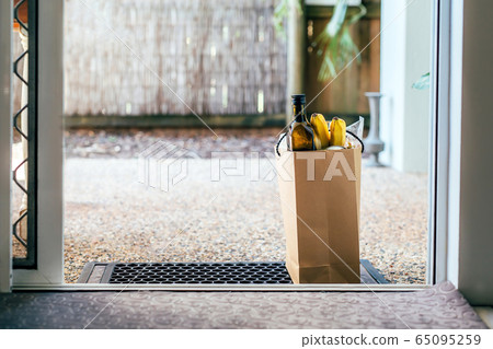 Paper bag with food and toilet paper on the floor at the entrance to house. Paper bag with food and toilet paper on the floor at the entrance to house. 65095259