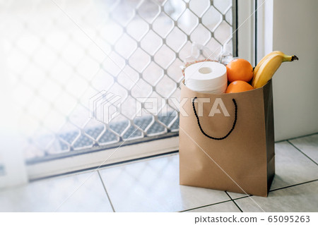Paper bag with food and toilet paper on the floor at the entrance to house. Paper bag with food and toilet paper on the floor at the entrance to house. 65095263