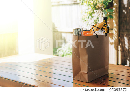 Paper bag with food on the wooden table in the backyard of a house. Paper bag with food on the wooden table in the backyard of a house. 65095272