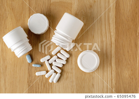 Two white bottles of tablets and a series of white and blue pills Two white bottles of tablets and a series of white and blue pills 65095476
