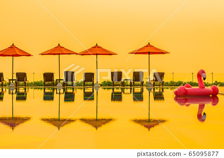 Beautiful sunrise around with umbrella and chair outdoor swimming pool 65095877