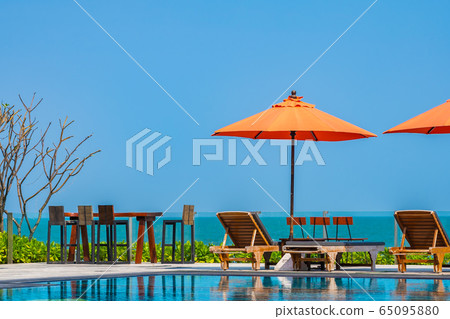 Umbrella and chair around outdoor swimming pool neary sea in hotel resort Umbrella and chair around outdoor swimming pool neary sea in hotel resort 65095880