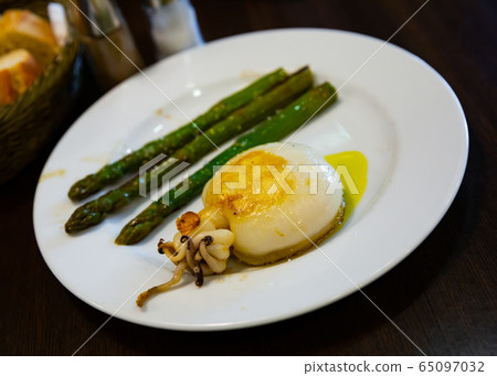 Deliciously baked squids with asparagus on a white plate Deliciously baked squids with asparagus on a white plate 65097032