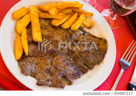 Appetizing calf steak with side dish of fried potatoes 65097117