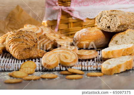 Wheat and grain baguettes, croissants and biscuits on wicker mat 65097375