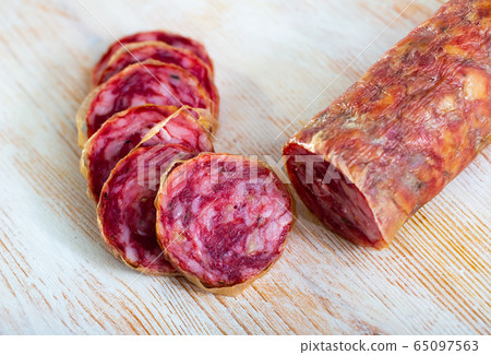 Thin salchichon sausage slices on wooden background, view from above Thin salchichon sausage slices on wooden background, view from above 65097563