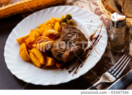 Appetizing steak in honey marinade with side dish of potatoes and olives Appetizing steak in honey marinade with side dish of potatoes and olives 65097566