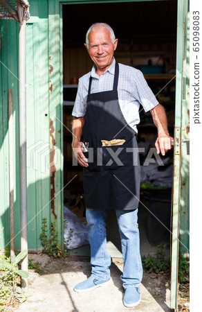 Happy man in doorway of garden shed Happy man in doorway of garden shed 65098083