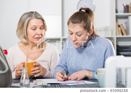 Woman with daughter filling documents 65098288