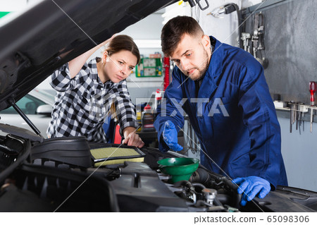Two masters are replacing the oil in the car in workshop. Two masters are replacing the oil in the car in workshop. 65098306