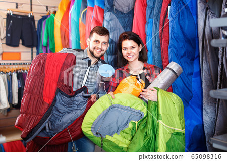Couple choosing touristic equipment in sports equipment store Couple choosing touristic equipment in sports equipment store 65098316