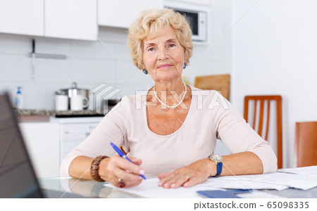 Senior woman filling up documents Senior woman filling up documents 65098335