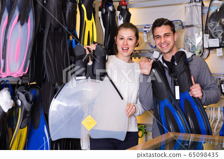 Man and woman are standing with modern diving flippers in the store. Man and woman are standing with modern diving flippers in the store. 65098435