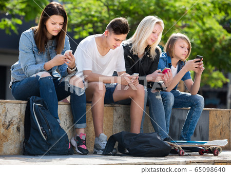 Teenagers looking at their mobile phones 65098640