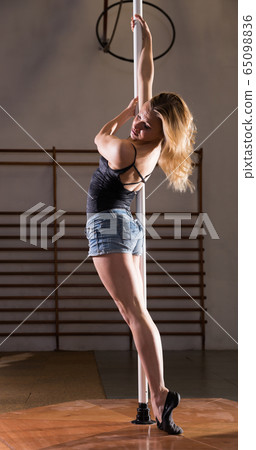 Attractive sports girl dancer engaged on pylon at gym Attractive sports girl dancer engaged on pylon at gym 65098836
