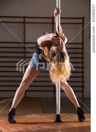 Attractive sports girl dancer engaged on pylon at gym Attractive sports girl dancer engaged on pylon at gym 65098837
