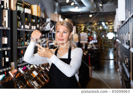 Smiling female winemaker holding glass of wine Smiling female winemaker holding glass of wine 65099063