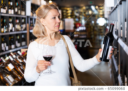 Cheerful middle aged woman tasting red wine 65099068