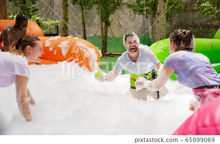 Game of funny friends in soap suds on an inflatable trampoline Game of funny friends in soap suds on an inflatable trampoline 65099069