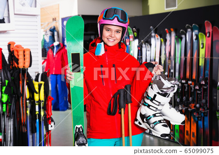 Woman standing with purchased ski equipment in shop Woman standing with purchased ski equipment in shop 65099075