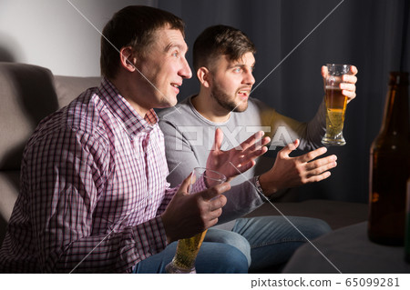 Two happy friends watching tv at home Two happy friends watching tv at home 65099281