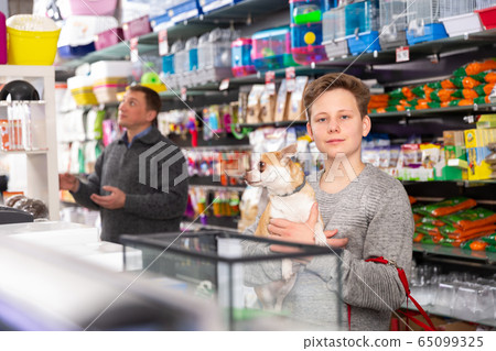Portrait of a boy with dog in petshop, man on background Portrait of a boy with dog in petshop, man on background 65099325