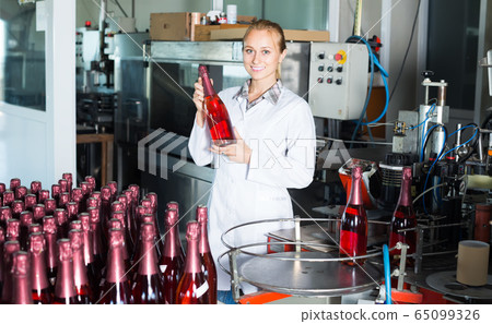 young woman holding newly produced bottles of wine young woman holding newly produced bottles of wine 65099326