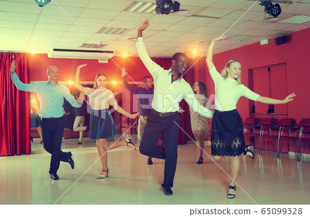 Young people practicing twist movements together at modern dance studio Young people practicing twist movements together at modern dance studio 65099328