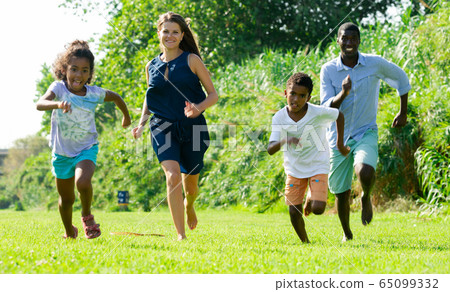 Happy children with parents running in park Happy children with parents running in park 65099332
