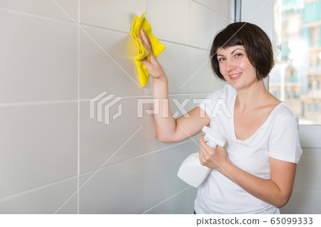 Woman cleaning tiled wall Woman cleaning tiled wall 65099333