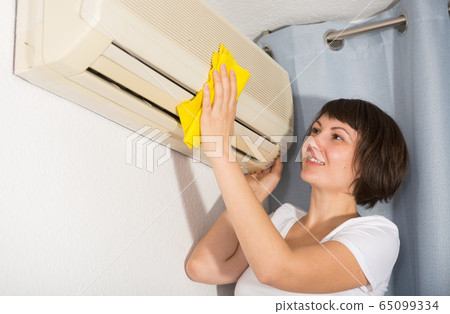 Woman washing her home air conditioner Woman washing her home air conditioner 65099334