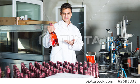 young man employee standing in final section of wine production on factory young man employee standing in final section of wine production on factory 65099335