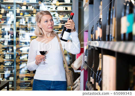 Nice woman inspecting quality of red wine Nice woman inspecting quality of red wine 65099343