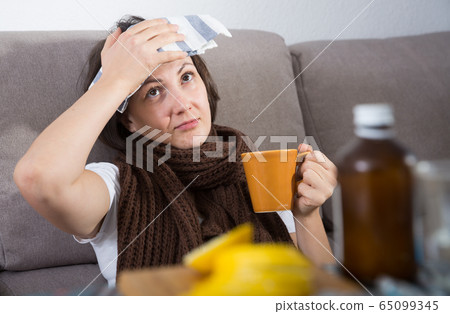 Sick woman lying on couch 65099345