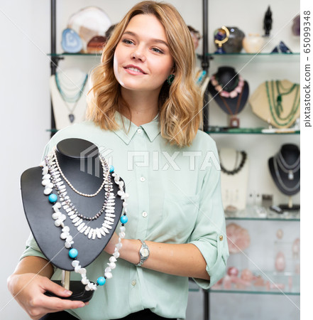 Salesgirl offering pearl necklaces 65099348
