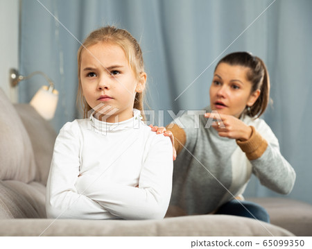 Frustrated small girl sitting at sofa, having conflict with mother Frustrated small girl sitting at sofa, having conflict with mother 65099350
