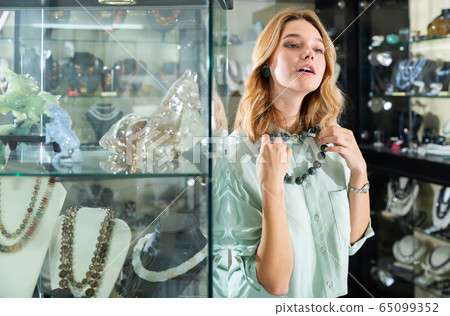 Girl trying on necklace made of natural stones 65099352