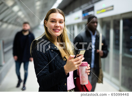 Young woman with phone waiting at subway station Young woman with phone waiting at subway station 65099448