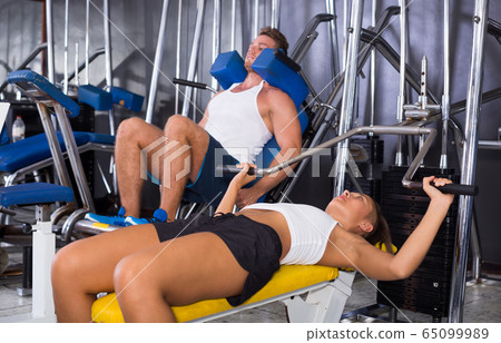 Young woman lifting weights in gym. Young woman lifting weights in gym. 65099989