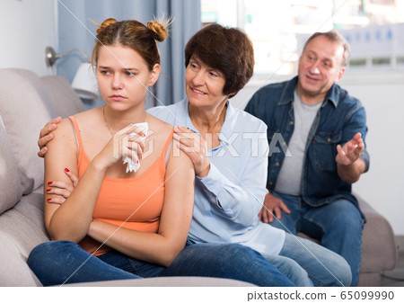 Parents are comforting the upset adult daughter on sofa Parents are comforting the upset adult daughter on sofa 65099990