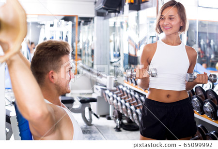 Woman training hands using weight dumbbells 65099992