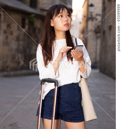 Young chinese female is looking up the way in phone by using gps Young chinese female is looking up the way in phone by using gps 65099999
