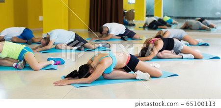 People relaxing and enjoying yoga in hall People relaxing and enjoying yoga in hall 65100113