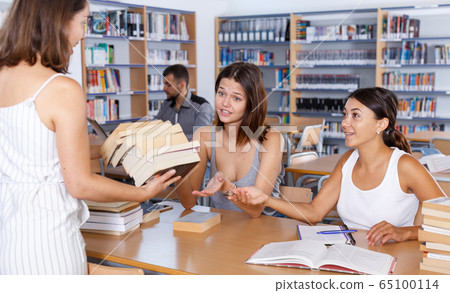 Female students taking books brought by librarian Female students taking books brought by librarian 65100114