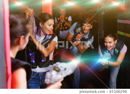 Portrait of happy young friends playing laser tag game with la 65100298