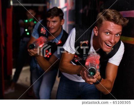 Young man with laser gun in dark labyrinth during laser tag game Young man with laser gun in dark labyrinth during laser tag game 65100305